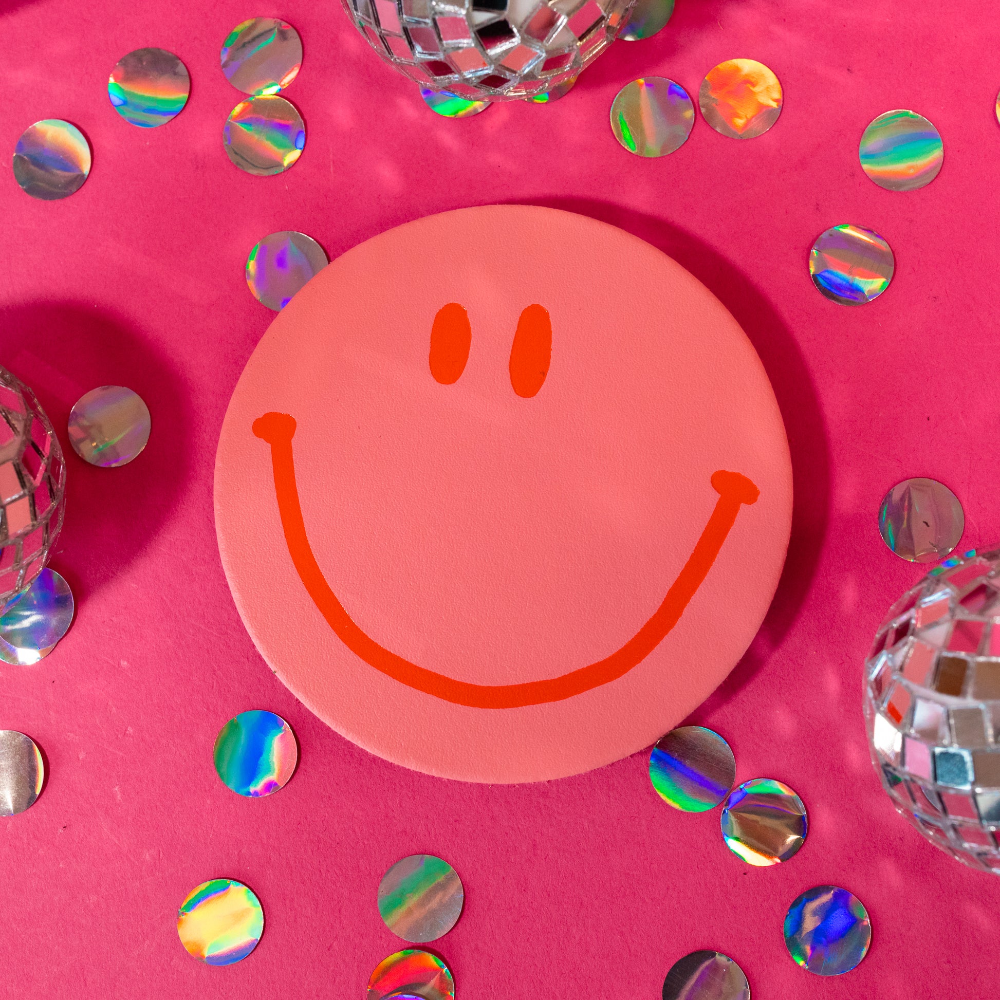 pink and orange smiley face coaster
