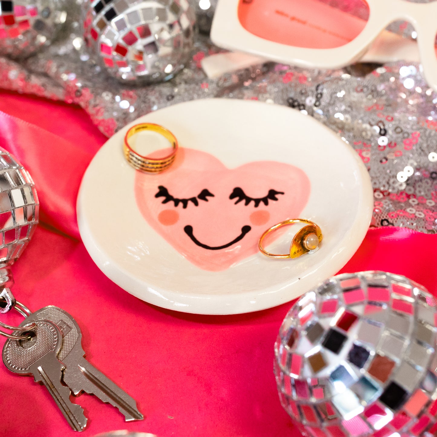 white dish with pink smiley heart and rings