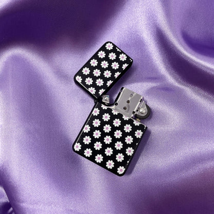 Trendy zippo style lighter with white and purple daisies on a black background.